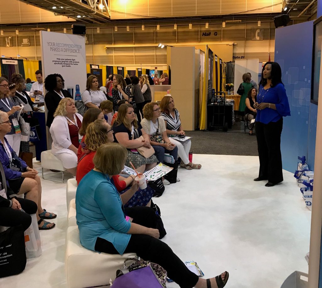 A presenter giving a live presentation to an audience at a trade show